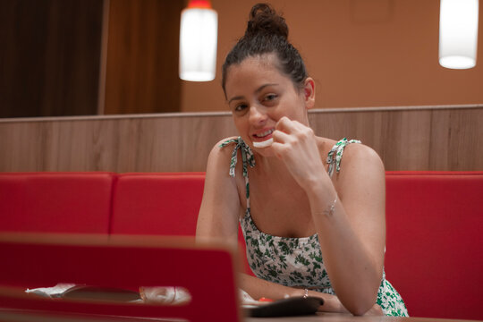 Mujer joven adolescente de pelo casta&ntilde;o masticando una patata frita en el restaurante para alimentarse en su cita romantica