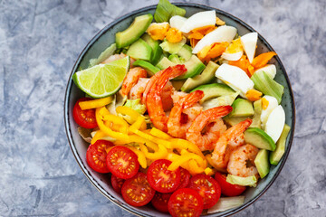 Delicious fresh salad with prawns, avocado, eggs, bell pepper, tomatoes and herbs