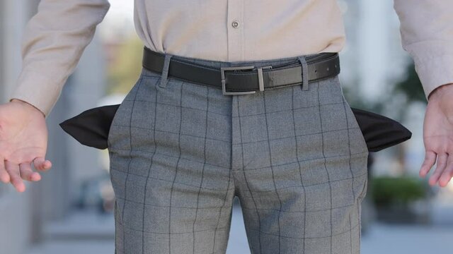 Close up male plaid pants. Man shows empty pockets standing outdoors isolated in city, poor bankrupt, no money financial crisis. Business bankruptcy debt problems, the guy suffers from unemployment.