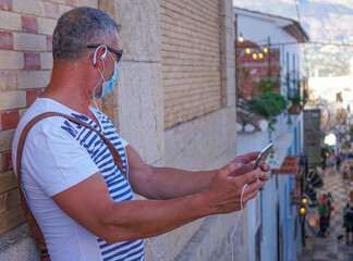 Hombre de mediana edad con mascarilla sanitaria de vacaciones en Altea con Tablet en video...