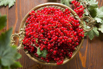 Fresh red currant in the rustic metal plate on a wooden table