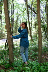 a pretty young woman in the forest wearing denim jeans and shirt.