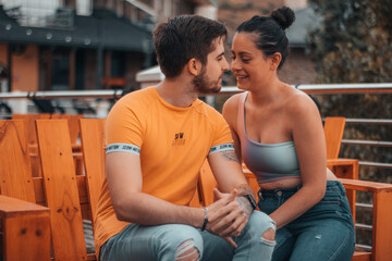 Jóvenes Enamorados sentados en un banco de una cafeteria mirándose para besarse