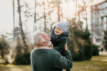 Grandfather enjoying with his grandson outdoors in the park.