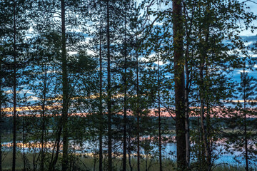 Obraz premium Northern nature - lake, forest. Pines and spruce trees on the banks of the river. Beautiful view. Sunset and sun.