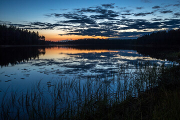 Fototapeta na wymiar Northern nature - lake, forest. Pines and spruce trees on the banks of the river. Beautiful view. Sunset and sun.