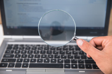 man holding magnifier with laptop