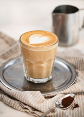 Flat white coffee with heart shaped foam milk on tray