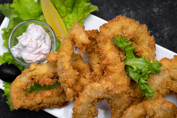 Squid rings fried in batter on a dark background soft focus