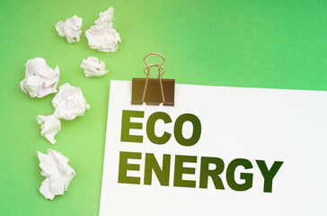 On a green background, crumpled paper and a sheet with the inscription - Eco energy