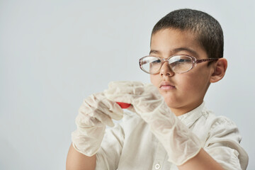 A portrait of cute boy in protective gloves and glasses making plasticine figures on the table