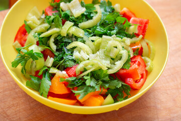 Vegetable salad with fresh tomatoes, peppers and parsley in a yellow cup. Delicious healthy snack