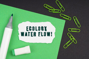 On a black background, a marker, paper clips, a sheet and torn paper with the inscription - Ecology Water Flow
