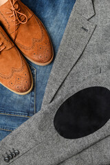 A pair of brown suede derby shoes and jeans on tweed blazer background. Top view.
