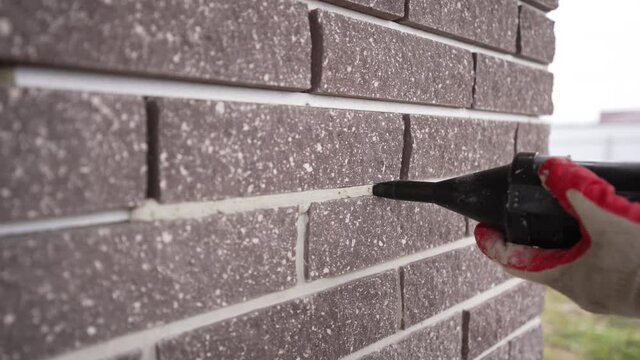 The master sews seams on the brickwork. Joints in brickwork. Grouting with tiling fugue. Repair in apartments and houses concept.