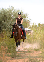 Girl rides a pinto horse at a trotting in the field