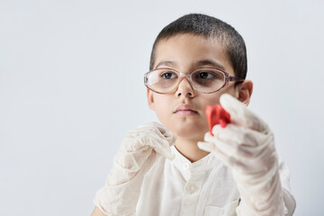 Portrait of a nerd boy in glasses playing with slime against the white background