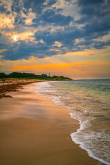 Fototapeta premium Nobska Lighthouse before sunrise with glowing golden light illuminating the green hill. Seascape with pink dawn sunrays over the Martha's Vineyard behind the lighthouse in Woods Hole, Massachusetts.