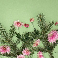 Bouquet of spruce sprigs and chrysanthemum flowers on green background with copy space