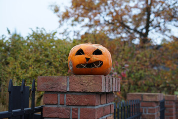 Halloween horror orange pumpkin as outdoor decoration idea on fence, autumn