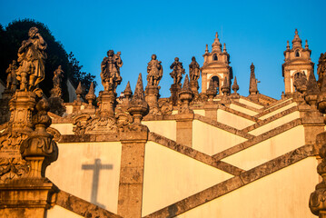 Obraz premium Zigzag shaped staircase of the church with numerous different statues and a cross shadow - Bom Jesus do Monte, Braga, Portugal, Vertical