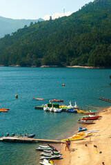 Fototapeta premium Geres National Park, Portugal - June 7, 2021: River beach with people, kayaks, jets and touristic boats - Portugal, Copyspace