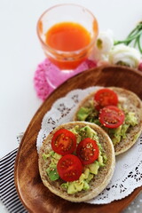 mashed avocado and cherry tomato in English muffin with carrot juice 
