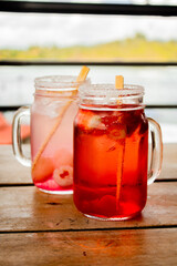 Tropical fresh soda with strawberry and lulu red and pink colors on wood table and window in Guatape Colombia