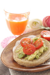 mashed avocado and cherry tomato in English muffin with carrot juice 