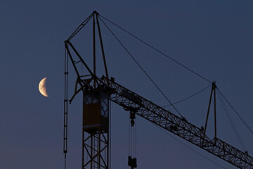 Schwarzarbeit im Baugewerbe. Ein Kran und der Mond am Nachthimmel