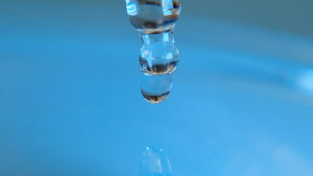 Hyaluronic acid.Glass pipette with a drop of hyaluronic acid on a blue background.Hyaluronic serum drops. Moisturizing the skin.Cosmetics and cosmetology concept. High quality 4k footage