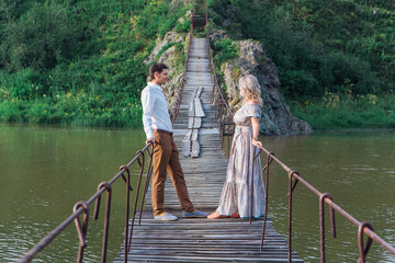 Beautiful young couple standing on the suspension bridge