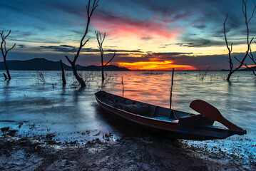 Alone fishing boat at lake with sunrise