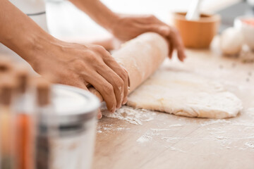 Obraz na płótnie Canvas Young woman rolling out dough in kitchen, closeup
