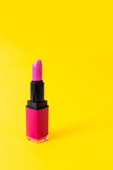 Close up of pink lipstick on yellow background. Beauty concept