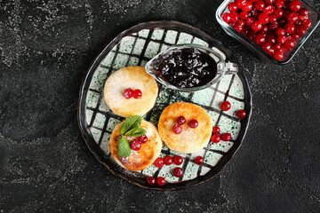 Plate with tasty cottage cheese pancakes. cranberry and jam on dark background