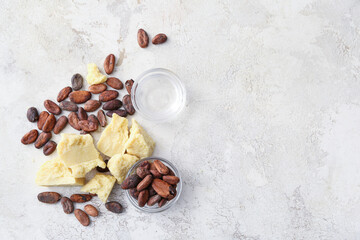 Pieces of cocoa butter and beans on light background