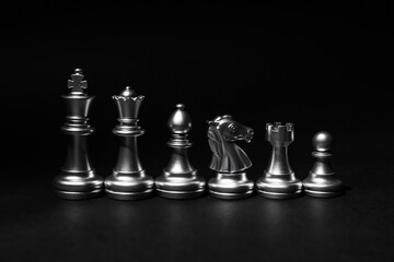 Silver chess pieces on dark background