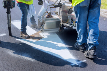 Worker thermoplastic spray marking machine painting work on the street