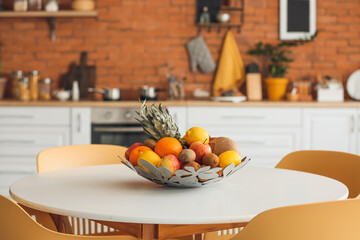Basket with fresh fruits on dining table in modern kitchen