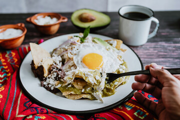 mexican chilaquiles with fried egg, chicken and spicy green sauce traditional breakfast in Mexico