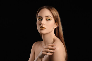 Fototapeta na wymiar Beautiful young woman with golden makeup on black background