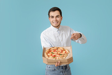 Handsome young man with tasty pizza on color background