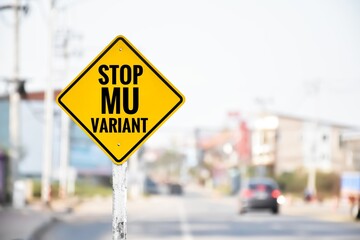 Traffic sign: ‘STOP MU VARIANT’ on cement pole beside the rural road with the blue and landscape background, copy space, concept for calling drivers to stop spreading new coronavirus now.