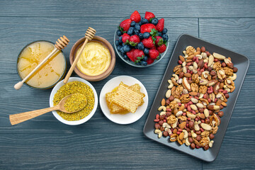 fresh assorted honey, nuts, strawberries and blueberries on a wooden background. healthy organic vitamin food.