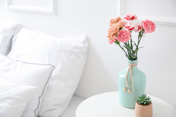 Vase with beautiful carnations on table in bedroom