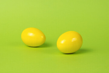 Two bright yellow eggs on a green background.