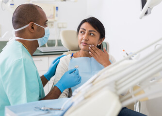 Woman patient talking to male dentist and complaining of toothache at dental clinic office