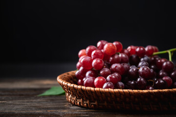Fresh red grape in a basket on wooden with black background, Organic tropical fruit, Still Life