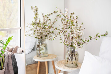 Vase with blossoming branches on table near mirror